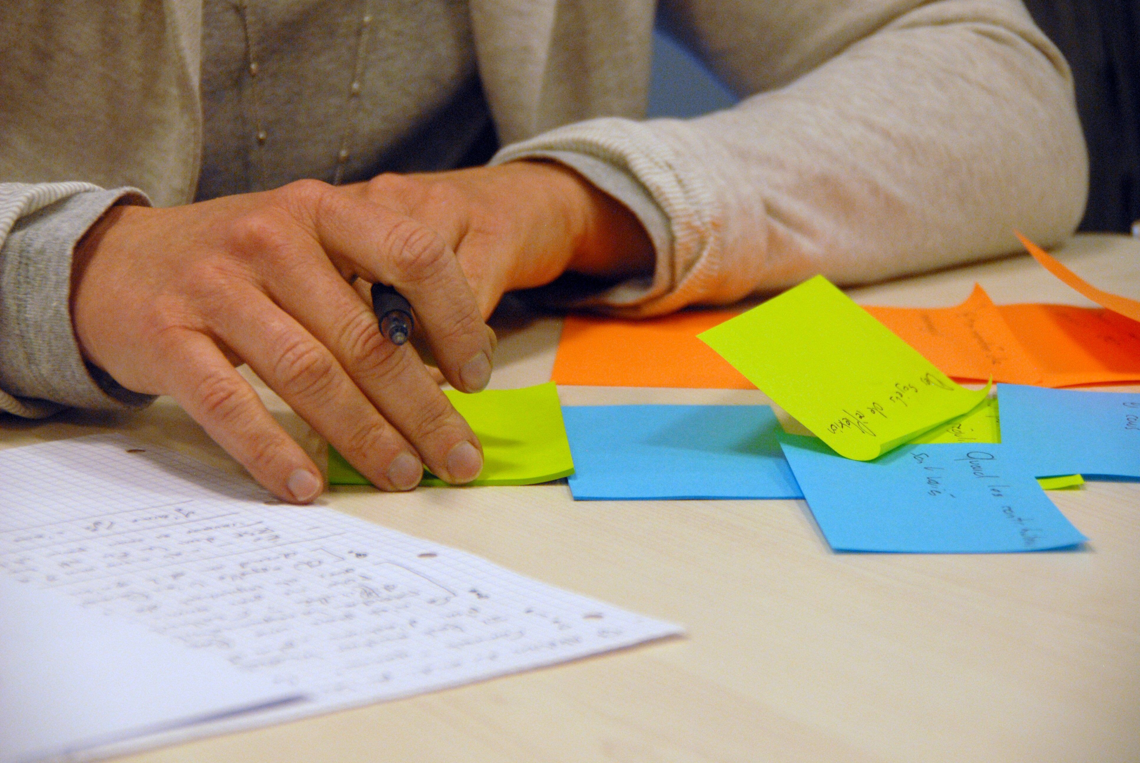 Eine Hand mit Stift, die auf Papier und Haftnotizen schreibt